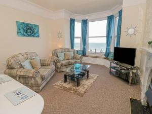 a living room with two couches and a tv at Llys Madoc, First Floor Flat in Penmaen-mawr