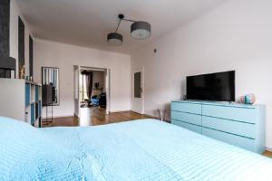 a bedroom with a large bed with a blue dresser and a tv at Blue House Warsaw Center in Warsaw