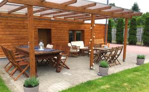 un patio con pergolato in legno, tavoli e sedie. di Marea Apartamenty Ustka a Ustka