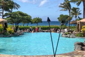 una piscina en un complejo con gente en el agua en Honua Kai en Lahaina