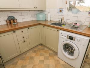 una cucina con lavatrice e lavandino di Bank End Cottage a Carnforth