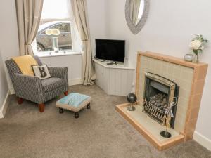 un soggiorno con camino, sedia e TV di Bank End Cottage a Carnforth