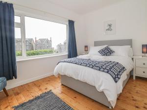 een slaapkamer met een bed en een groot raam bij Nefydd in Criccieth