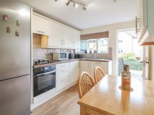 eine Küche mit weißen Schränken und einem Holztisch in der Unterkunft Lavender Cottage in Ilkeston