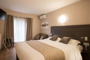 a bedroom with a large bed and a window at Logis Hotel Le Petit Casset in La Boisse