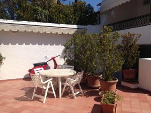 einen Tisch und Stühle auf einer Terrasse mit Topfpflanzen in der Unterkunft Elegante Villa al centro di Ischia Porto in Ischia