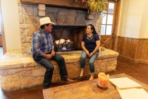 a man and a woman sitting on a stone fireplace at Wildcatter Ranch and Resort in Graham