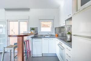 エンプリアブラバにあるApart-rent Apartment Gran Reserva 0061の白いキャビネットと木製テーブル付きのキッチン