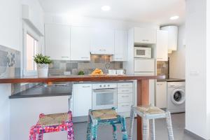 una cocina con armarios blancos y una barra con taburetes en Apart-rent Apartment Gran Reserva 0061, en Empuriabrava