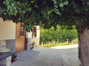 a building with a wooden door and a tree at CASA RURAL Arriaran in Leitza