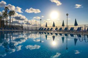 een zwembad met stoelen en de zon in de lucht bij Stunning Views Guaranteed in Taurito