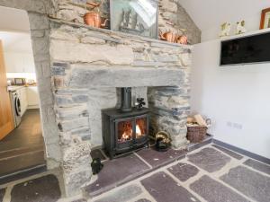 a stone fireplace with a stove in a room at Pen Y Braich Uchaf in Brynkir