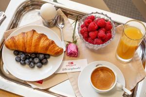 a tray with a plate of fruit and a cup of coffee at Sofia Palace Hotel by HMG in Sofia
