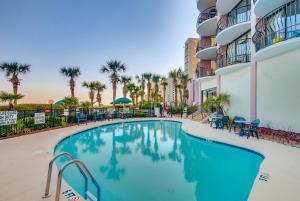 a pool at a resort with chairs and palm trees at Oceanfront Penthouse, Two-Story, 3 Bedrooms in Myrtle Beach