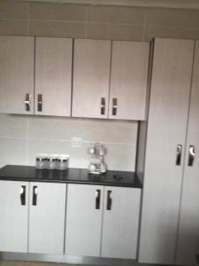 a kitchen with white cabinets and a black counter top at Hunters Self Catering Apartment in East London