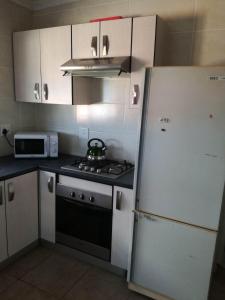 een keuken met een fornuis en een witte koelkast bij Hunters Self Catering Apartment in East London