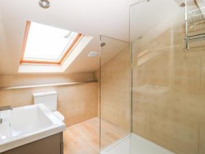 a bathroom with a glass shower and a sink at The Old Shippon in Keighley