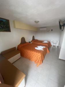 a hotel room with two beds with orange comforter at Hotel del Angel in Catemaco