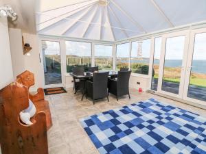 a dining room with a table and chairs and windows at Golygfa Ynys Island View in Amlwch