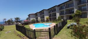 a building with a pool in front of a building at 24 Topanga in Uvongo Beach