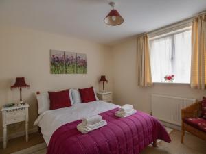 a bedroom with a bed with a purple blanket at Little Barn in Wincanton