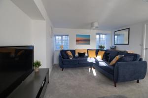 a living room with a blue couch and a tv at Willowbrook Cottage in Bridport