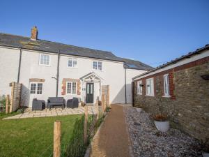 a white house with a patio in front of it at Willowbrook Cottage in Bridport