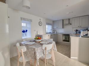 a kitchen with a table and chairs and a kitchen with white cabinets at Willowbrook Cottage in Bridport