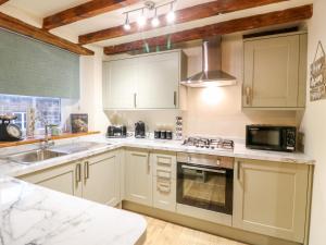 a kitchen with white cabinets and a sink and a microwave at Milford Cottage in Belper