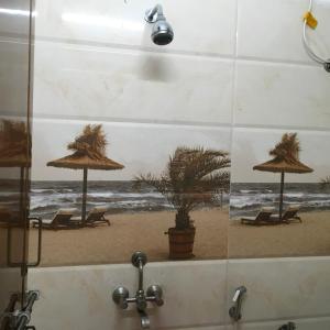a bathroom with a picture of a beach with chairs and umbrellas at Jayaram Residency Srikalahasti in Srikalahasti