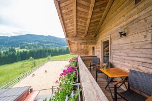 a porch of a wooden cabin with a table and flowers at Ferienwohnung Schoberhof in Filzmoos