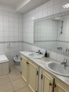 een badkamer met 2 wastafels, een toilet en een spiegel bij Seaside doors in Vila Real de Santo António +37 foto's