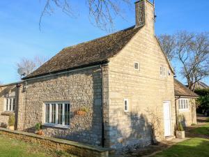 un antiguo edificio de piedra con chimenea en la parte superior en Half Acre Cottage Annexe, en Peterborough