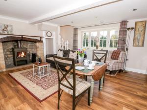 ein Wohnzimmer mit einem Tisch und einem Kamin in der Unterkunft Half Acre Cottage Annexe in Peterborough