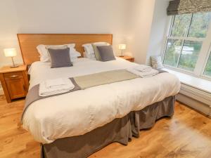 a large bed in a bedroom with two windows at Pearsall in Ambleside