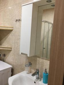y baño con lavabo blanco y espejo. en Kvariati apartamenrs en Kvariati