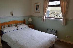 a bedroom with a white bed and a window at Bachylis Self Catering in Kirkwall
