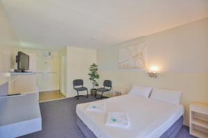 a hotel room with a bed and a chair at Oscar Motel in Bundaberg