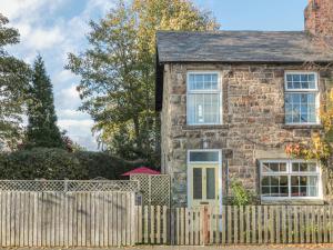 an old stone house with a wooden fence at Wordsworth Cottage West in Morpeth