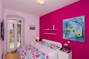 a bedroom with a pink wall and a bed at Apartment Djivo in Dubrovnik