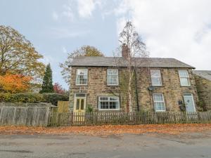 a brick house with a fence in front of it at Wordsworth Cottage West in Morpeth