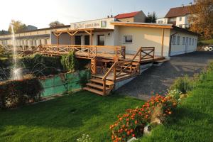 a building with a deck in a yard with flowers at Luční penzion in Česká Skalice