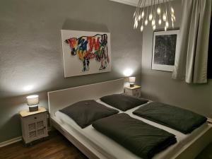 a bedroom with a bed with a cow painting on the wall at Gruga Apartment an der Messe in Essen