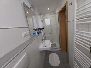 een witte badkamer met een wastafel en een spiegel bij Appartment Vermietung Lütje in Büsum