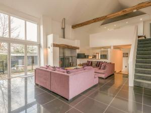 a living room with two pink couches and a kitchen at Flint Barn in North Walsham