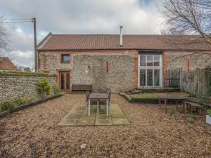 a brick house with a table and chairs in the yard at Flint Barn in North Walsham