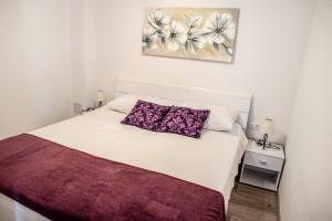 a bedroom with a white bed with purple pillows at Bilić S in Dugi Rat