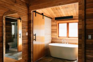 La salle de bains est pourvue d'une baignoire blanche et d'une fenêtre. dans l'établissement Bodega Ridge & Cove Cabins, à Fernwood