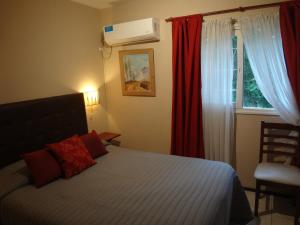 een slaapkamer met een bed met rode gordijnen en een raam bij Depto en Parque Central in Mendoza