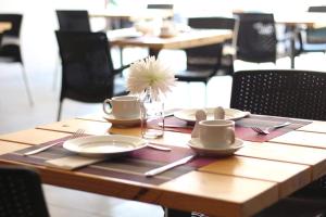 a wooden table with plates and a flower in a vase at Copperwood Hotel and Conferencing in Brits